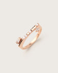 Rose gold ring with a modern flat-top design, showcasing a row of round, baguette, and princess-cut diamonds, set against a soft neutral background.