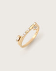 Modern yellow gold ring featuring a sleek, asymmetrical design with baguette, round, and princess-cut diamonds set in a row, displayed on a light background.