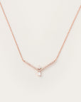 Delicate rose gold necklace featuring a V-shaped diamond-accented frame with a pear-cut diamond and a baguette-cut diamond pendant.