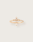 Delicate yellow gold ring featuring a vertical arrangement of baguette and round diamonds in a cross-like design, set against a soft neutral background.
